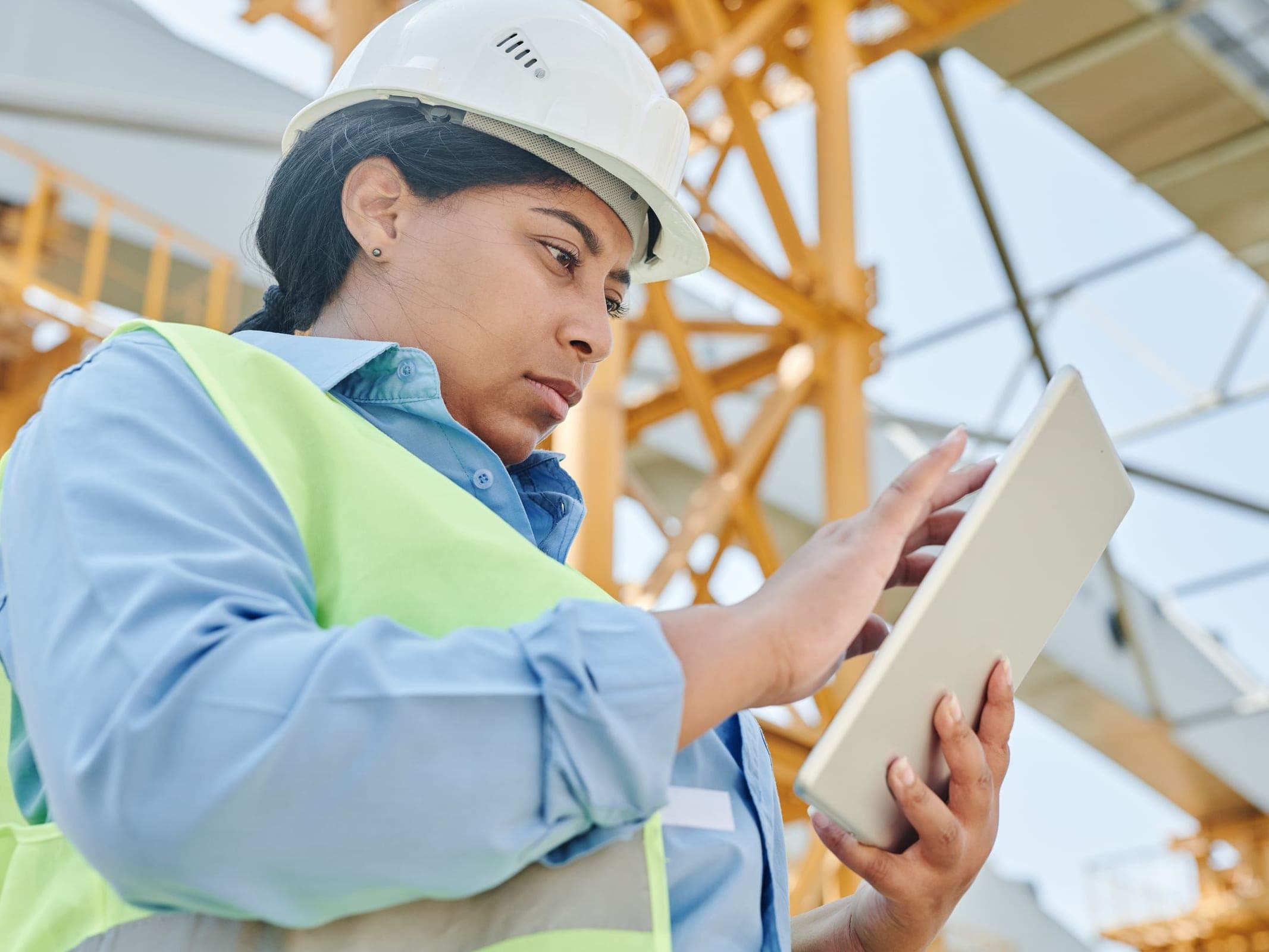 Industrial worker in a safety helmet reviewing a tablet at a construction site
