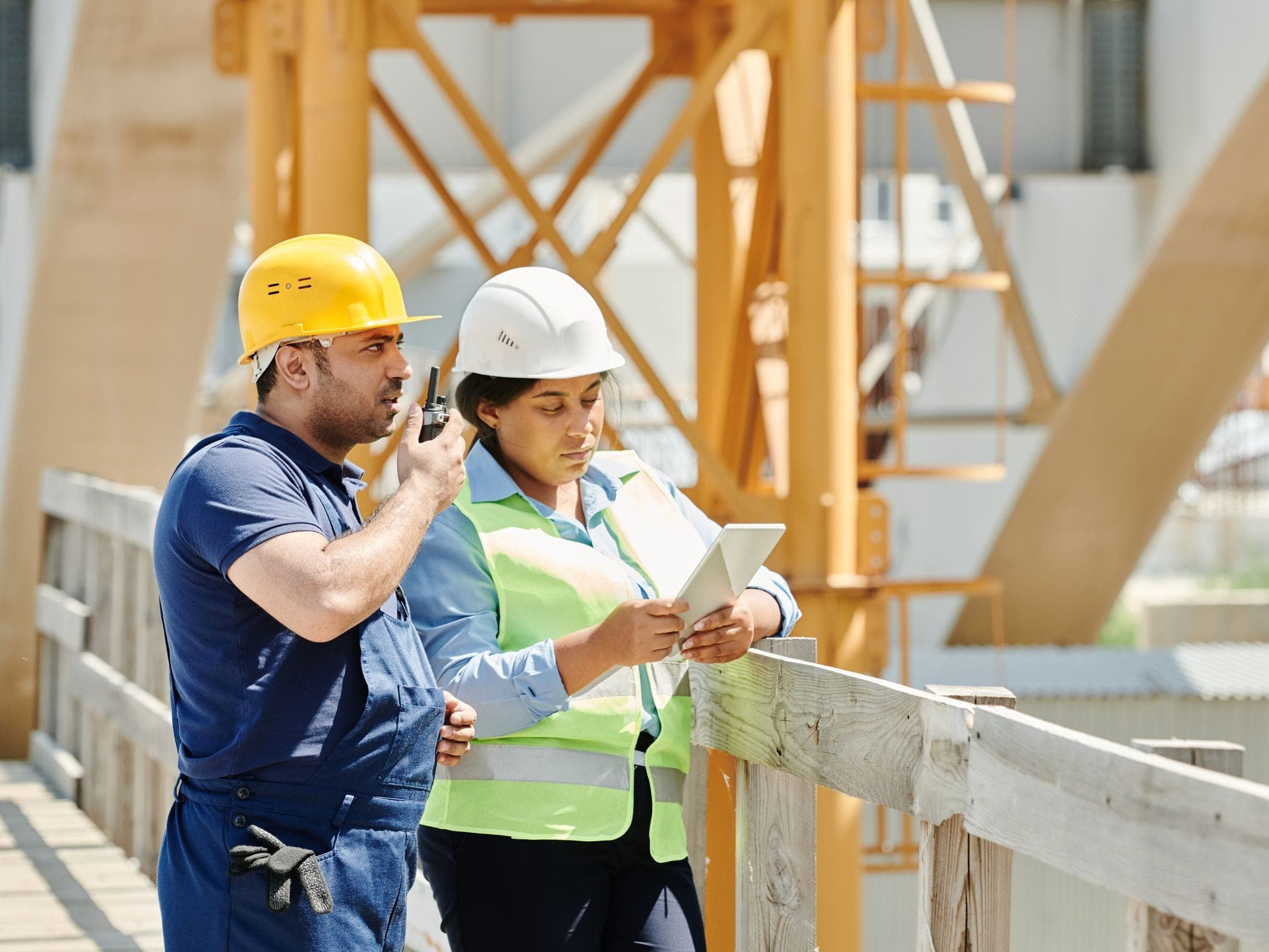 Field worker in high-visibility gear beside heavy equipment on site