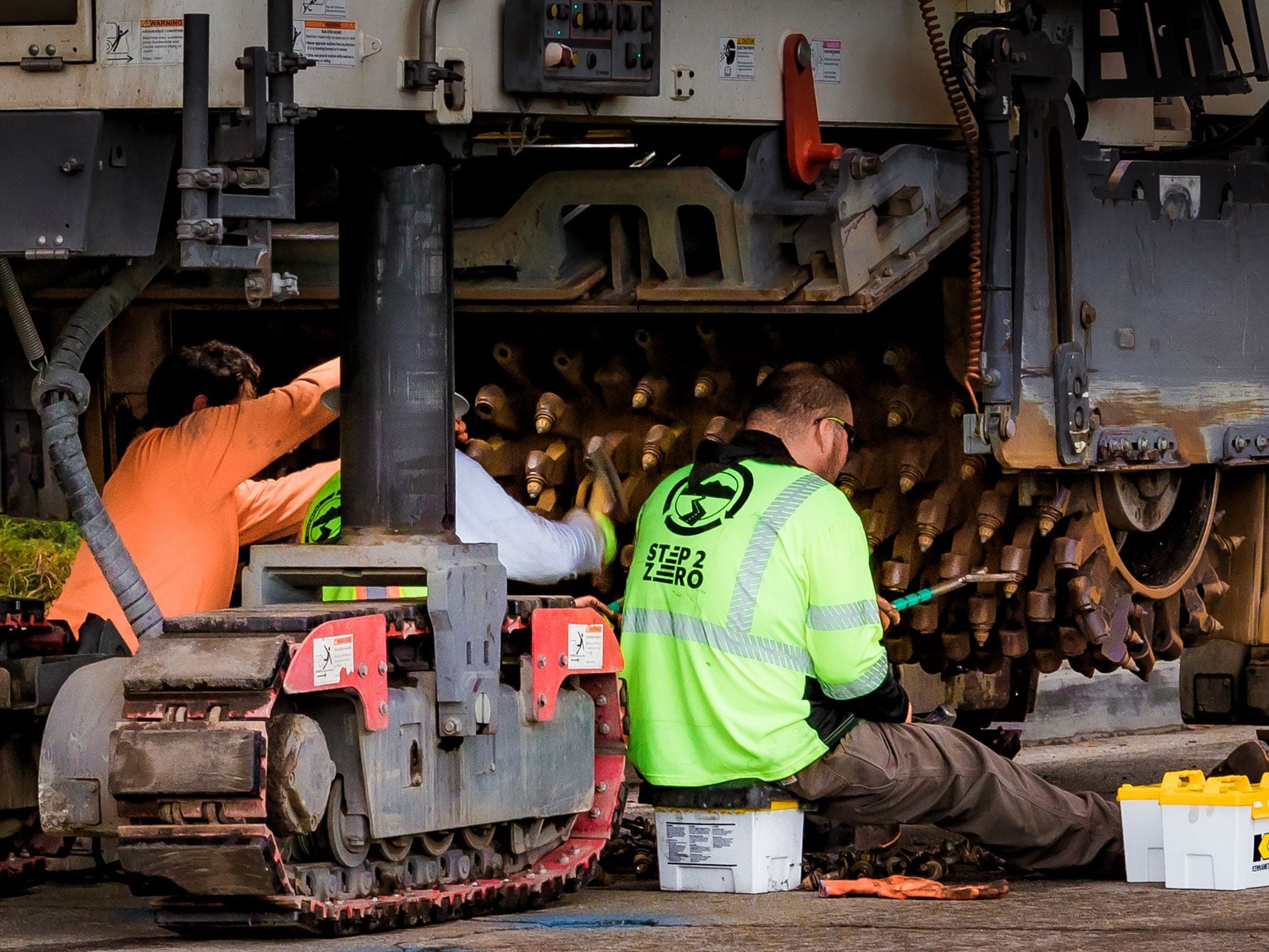 Maintenance technician with tablet next to excavator