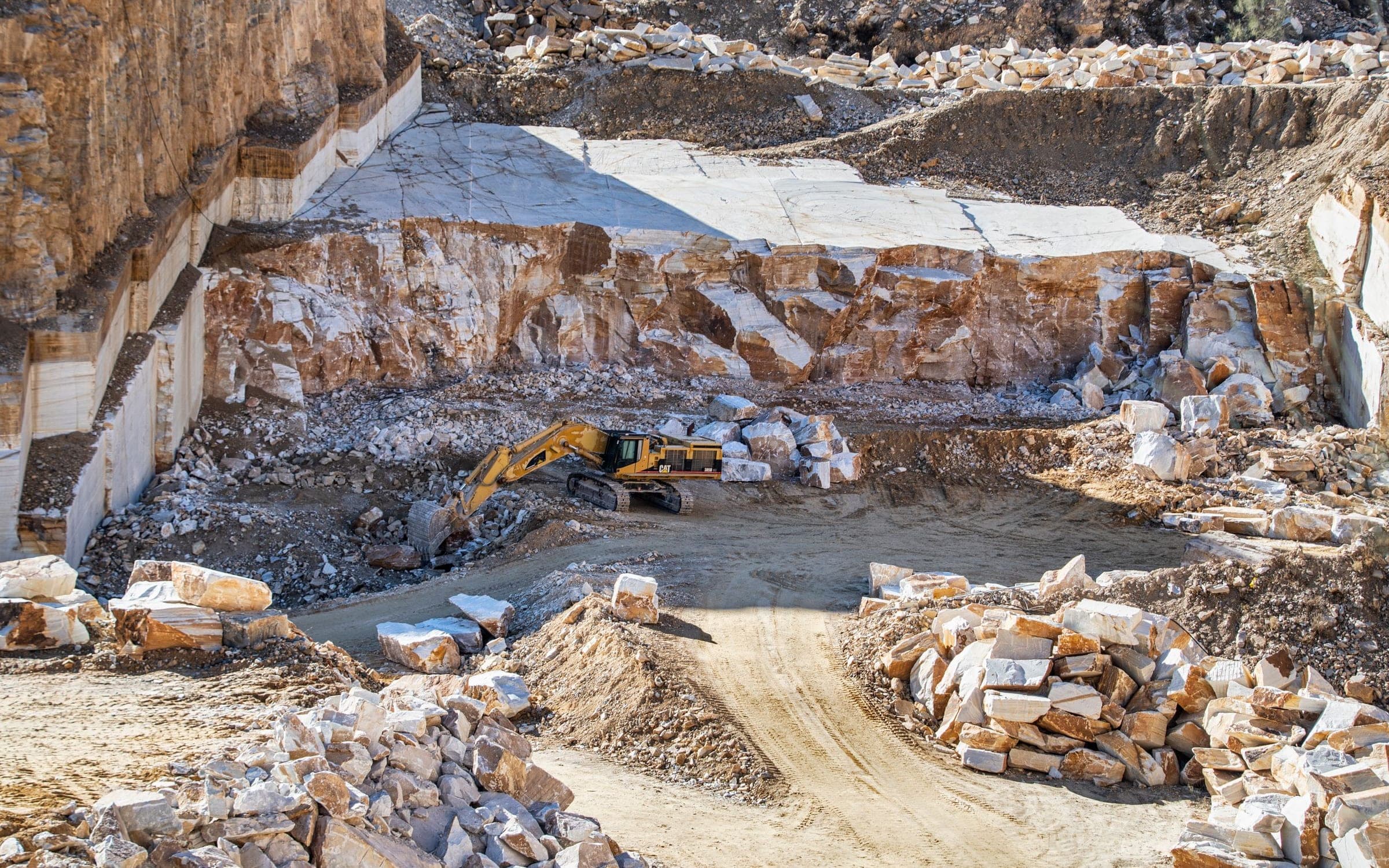 Excavator with heavy-duty breaker attachment in an industrial quarry